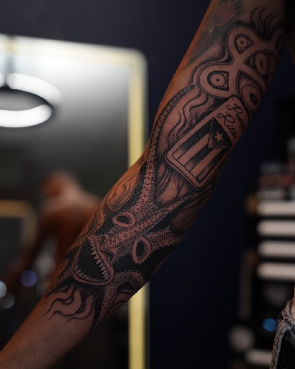 Black and grey giant squid sleeve with taíno sun and Puerto Rico flag on the forearm, by Rodney Alacan