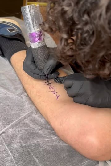 Israel Crespo tattooing lettering on a forearm