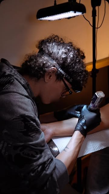 Israel Crespo tattooing under a headlamp